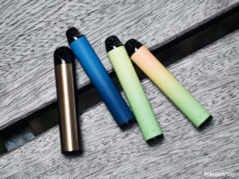 Disposable vape devices sit on a wooden bench in an array of colours.