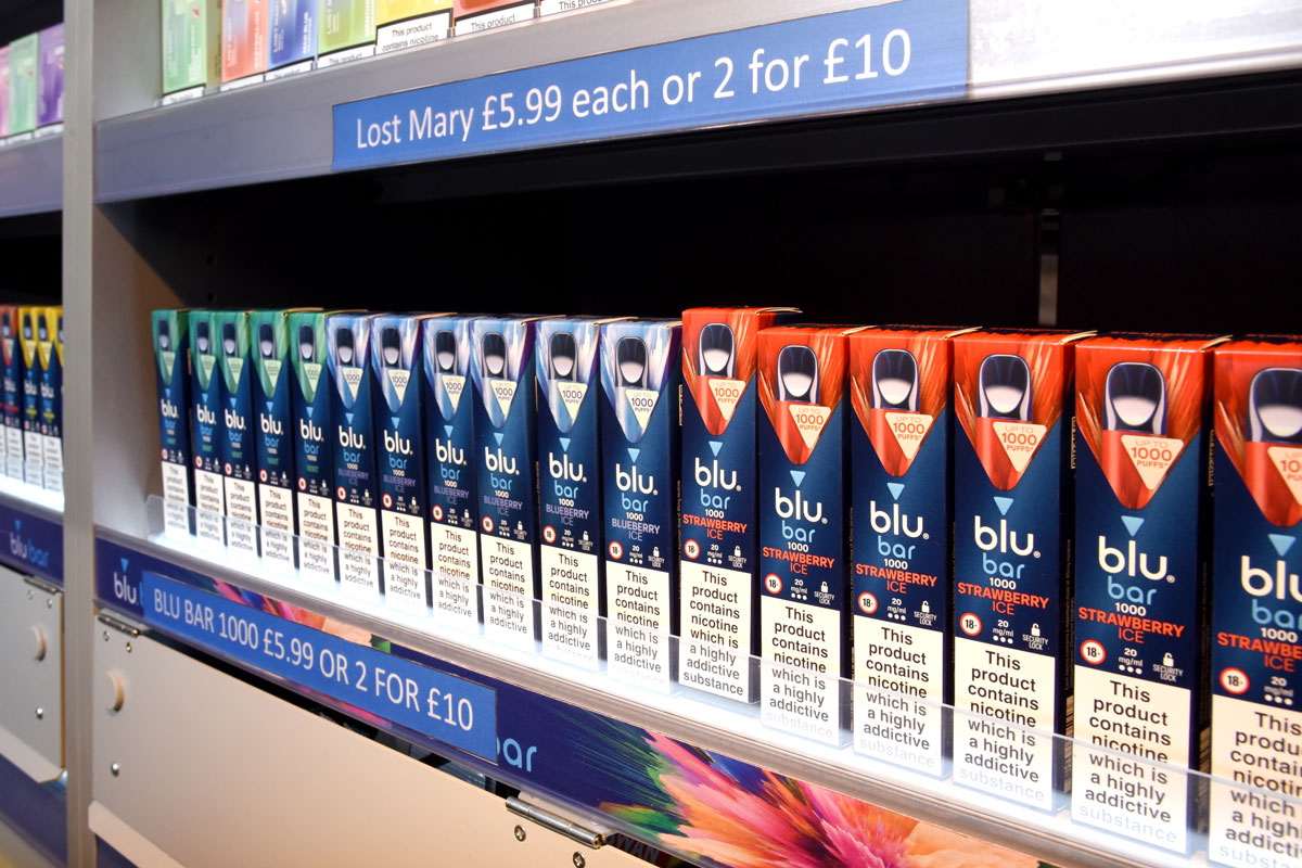 A row of Blu Bar disposable vapes in a gantry.