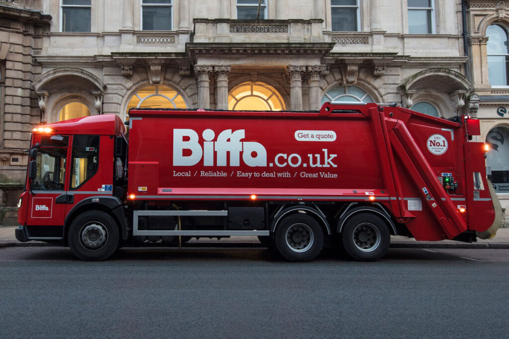 A Biffa branded waste disposal truck is parked outside of a building.