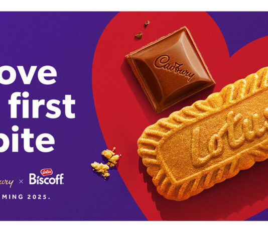 Cadbury announces new partnership with Lotus Biscoff Promotional image for the team up of Cadbury and Lotus Bakeries with a piece of Cadbury Dairy Milk chocolate and a Lotus biscuit side by side in a red love heart with text on the left reading 'Love at first bite'.