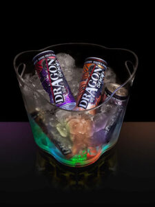 An ice bucket with cans of Dragon Soop and lighting inside against a black background.