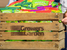 Growers Garden grows in multiples A person carrying a wooden crate with the Growers Garden logo burned on to it with packs of Broccoli Chips inside the crate.