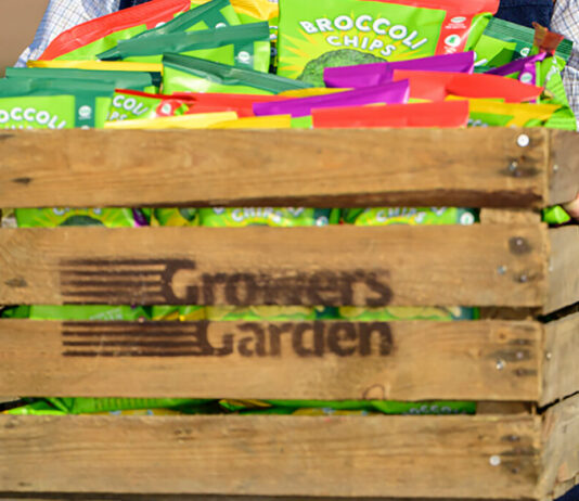 Growers Garden grows in multiples A person carrying a wooden crate with the Growers Garden logo burned on to it with packs of Broccoli Chips inside the crate.