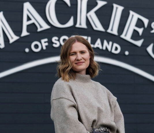 Mackie’s fires up frozen sales Kirsten Blockley, national account manager at Mackie's of Scotland, stands in front of the Mackie's of Scotland sign.