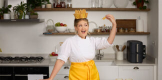 Social media influencer Poppy O'Toole stands wearing a crown made of chips in front of food dishes containing McCain's Air Fryer range.