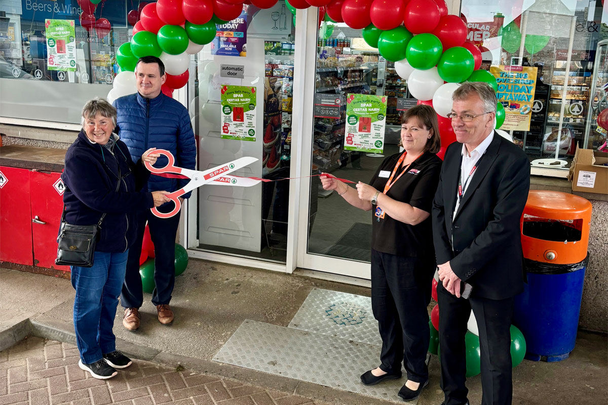 Reopening of Spar Nairn forecourt with red and green balloons over the door as a group of four people stand around the entrance with one of them holding large, novelty scissors to cut the ribbon.
