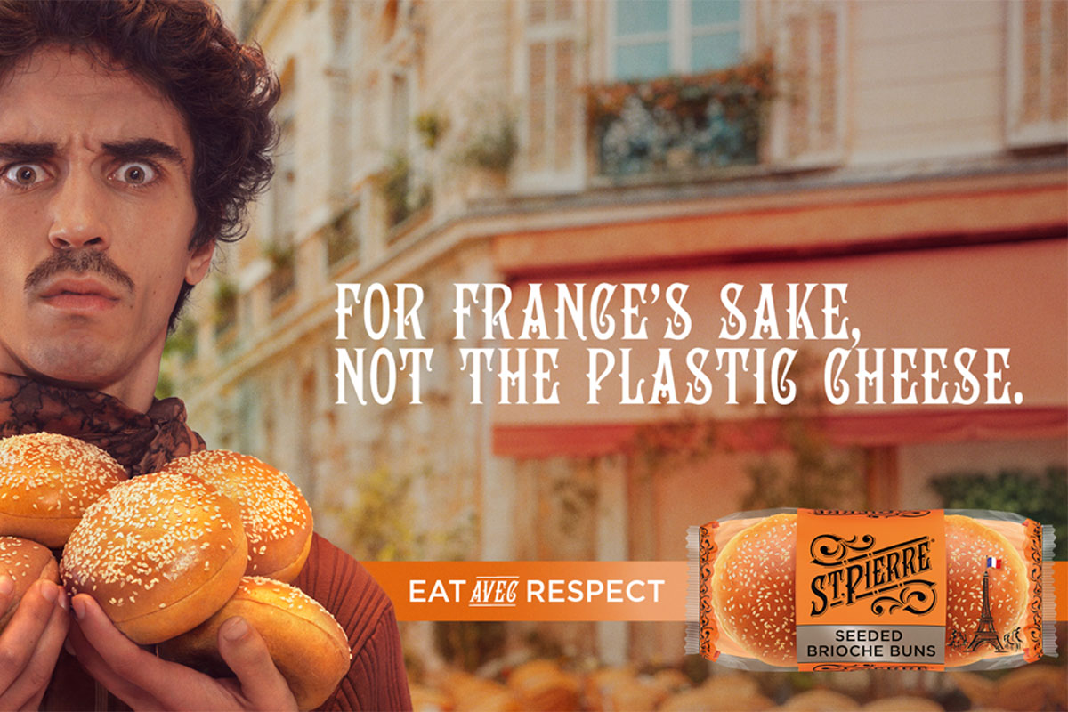 Visual from the St Pierre ATL campaign featuring a man holding sesame seed brioche burger buns with a pack of St Pierre Sesame Seed Burger Buns in the bottom left with the phrase "For France's sake, not the plastic cheese'