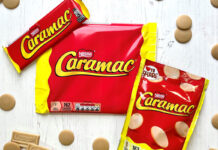 Packs of Caramac including a bar, multipack of bars and sharing pack, sit on a white wooden background with pieces of the blonde chocolate around them.