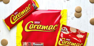 Packs of Caramac including a bar, multipack of bars and sharing pack, sit on a white wooden background with pieces of the blonde chocolate around them.