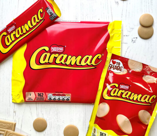 Caramac is back on the shelves Packs of Caramac including a bar, multipack of bars and sharing pack, sit on a white wooden background with pieces of the blonde chocolate around them.