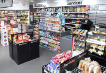 A Day-Today store floor with the counter area, product bins close to the checkout and a staff member behind the till.