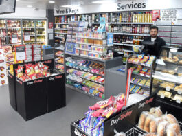 Inflation trickles down on consumer goods A Day-Today store floor with the counter area, product bins close to the checkout and a staff member behind the till.