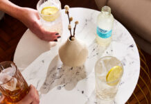 Drinks sit on a white marble table with a bottle of Franklin & Sons Sicillian Lemon on the table next to a vase.