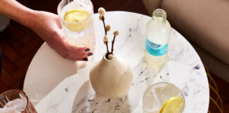 Drinks sit on a white marble table with a bottle of Franklin & Sons Sicillian Lemon on the table next to a vase.