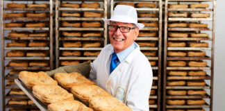 Gordon Allan holds a tray of steak pies with trays stacked up behind him.