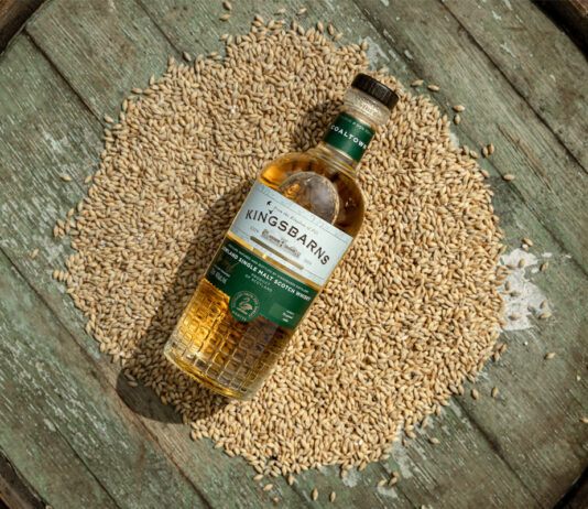 Kingsbarns honours history in new whisky launch A bottle of Kingsbarns Coaltown lies on top of a pile of grain on top of a wooden barrel.