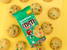 Add in colour with new M&M’s Minis Cookies A pack of M&M's Minis Cookies sit on top of a yellow background with the cookies around the pack.