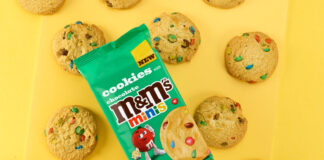 A pack of M&M's Minis Cookies sit on top of a yellow background with the cookies around the pack.