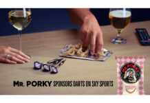 People pick from an open pack of Mr Porky pork scratchings with darts on the table and drinks around their hands, text reads "Mr. Porky sponsors Darts on Sky Sports".