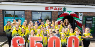 A group of people stand in front of Spar Garthamlock holding a £500 sign wearing yellow shirts.