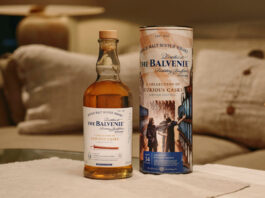 Open up to Curiosity with new whisky from The Balvenie A bottle of The Balvenie A Collection of Curious Casks 14 Year Old American Bourbon Barrel stands next to its case on top of a white couch.