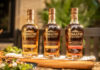 Bottles from the Tomatin Sherry Cask Collection are lined up on a table together including The Manzanilla Edition, The Palo Cortado Edition and the Pedro Ximénez Edition.
