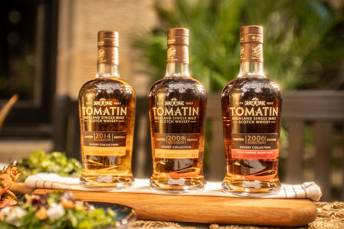 Bottles from the Tomatin Sherry Cask Collection are lined up on a table together including The Manzanilla Edition, The Palo Cortado Edition and the Pedro Ximénez Edition.