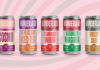 Cans of Wonderland Cocktails sit in front of a pink, white and grey spiral design.