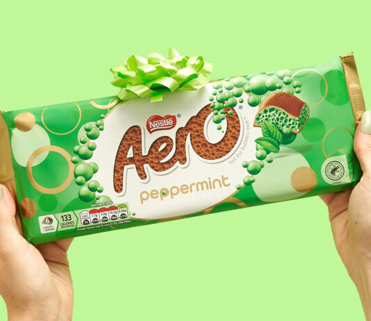 Aero unwraps the gifting opportunity in new bar A person holds an Aero Peppermint Sharing Bar against a green background with a green bow on top of the bar.