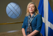 Gillian Martin, acting net zero secretary, stands in Scottish Parliament with the Scotland flag behind her.