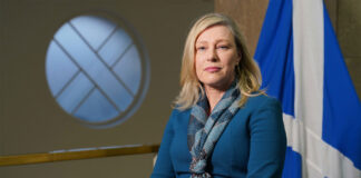 Gillian Martin, acting net zero secretary, stands in Scottish Parliament with the Scotland flag behind her.