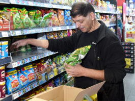 Inflation rises for the first time in a year A man is stocking shelves with crisps in a convenience store.