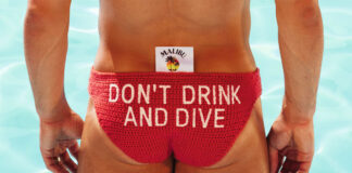 Olympic diver Tom Daley stands in front of a pool in diving clothing with a Malibu branded tag sticking out the clothes with the text reading 'Don't Drink and Dive'.