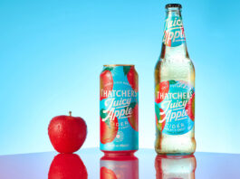Thatchers Cider rolls a Juicy launch to retail A bottle of Thatchers Juicy Cider Juicy Apple is next to a can of Thatchers Cider Juicy Apple with a red apple next to the can against a blue background with a shiny red table underneath.
