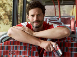 Jamie Dornan partners with Diet Coke Jamie Dornan sits on a bus leaning over seats holding a can of Diet Coke.