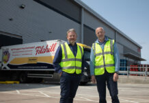 Simon Hannah, group chief executive officer at JW Filshill,(left) and Keith Geddes, chief financial and operating officer, (right) stand in front of the JW Filshill depot with one of the wholesaler's HGV vehicles behind them.