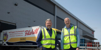 Simon Hannah, group chief executive officer at JW Filshill,(left) and Keith Geddes, chief financial and operating officer, (right) stand in front of the JW Filshill depot with one of the wholesaler's HGV vehicles behind them.