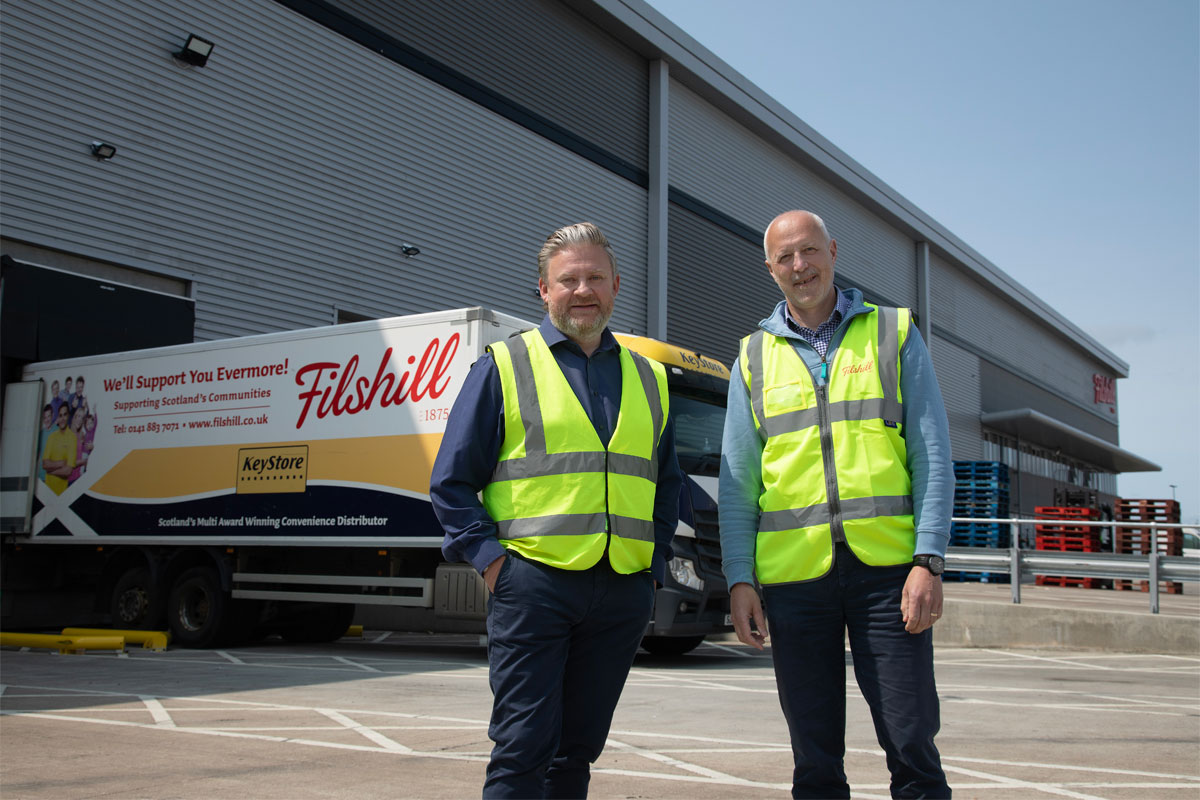 Simon Hannah, group chief executive officer at JW Filshill,(left) and Keith Geddes, chief financial and operating officer, (right) stand in front of the JW Filshill depot with one of the wholesaler's HGV vehicles behind them.