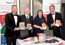 Members of the GroceryAid Scotland board stand at a table at the Scottish Grocer Awards 2022 to raise funds for the charity.