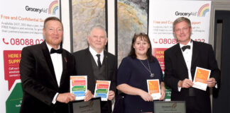 Members of the GroceryAid Scotland board stand at a table at the Scottish Grocer Awards 2022 to raise funds for the charity.