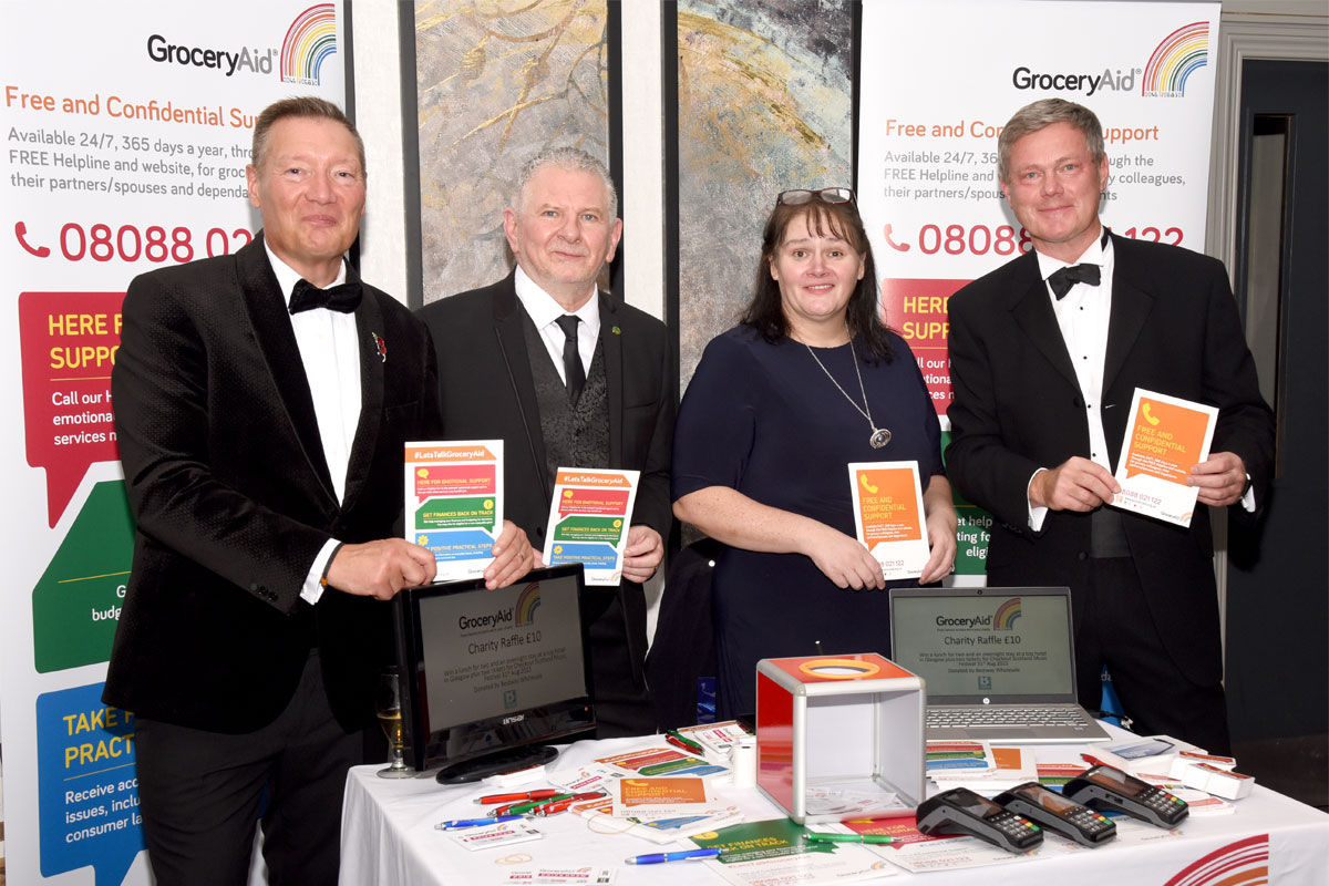 Members of the GroceryAid Scotland board stand at a table at the Scottish Grocer Awards 2022 to raise funds for the charity.