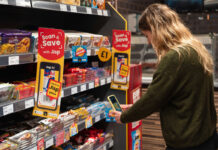 A woman uses her phone to redeem rewards of Jisp's Scan & Save app with promotions highlighting the app on store shelves.