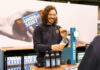 A person stands at a Lucky Saint branded beer tap pulling a pint with bottle of Lucky Saint in front of him.