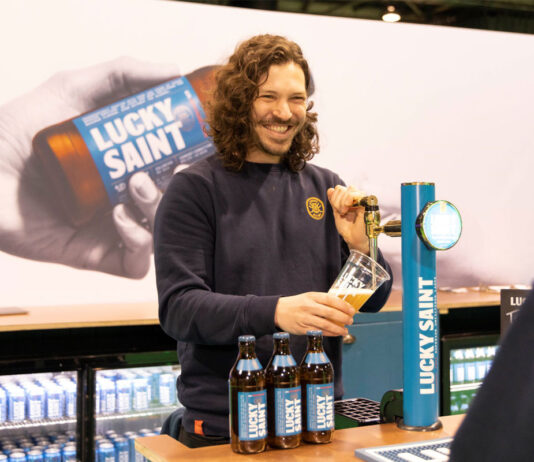 In-Drinks Glasgow launches 2025 show A person stands at a Lucky Saint branded beer tap pulling a pint with bottle of Lucky Saint in front of him.