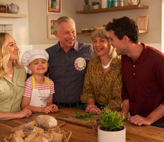 OXO is back on TV for the autumn A family gather round a kitchen table together looking happy, still image taken from OXO TV advert.