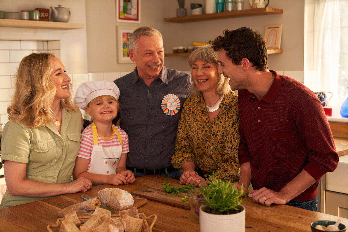 A family gather round a kitchen table together looking happy, still image taken from OXO TV advert.