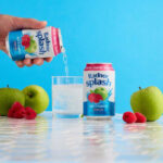 Market News | Hovis, Shaken Udder, STG, Radnor Hills Lifestyle image of a person pouring a can of Radnor Splash into a glass with another can next to the glass and fruit around it.