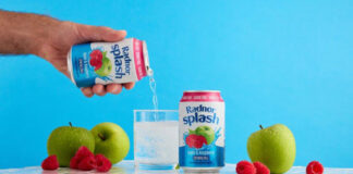 Lifestyle image of a person pouring a can of Radnor Splash into a glass with another can next to the glass and fruit around it.