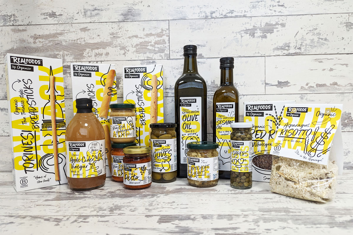 A range of foods of Realfoods by Organico sit on a countertop with a grey background.