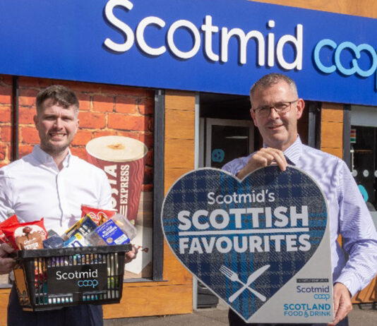 Scotmid Scottish Favourites returns Two people stand outside a Scotmid store, one person holds a sign for the Scotmid Scottish Favourites Competition while the other holds a basket filled with Scottish produce.